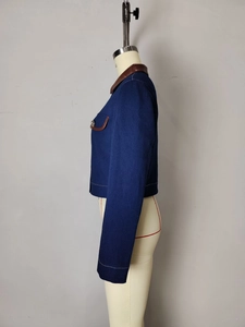 Detail of navy denim jacket featuring brown leather collar and metal button accents