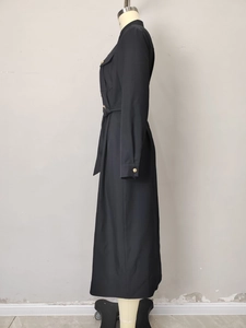 Detail view of black shirt dress with golden buttons and waist tie belt on a mannequin