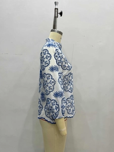 Detail of the stand collar and blue embroidery on the white casual women's shirt