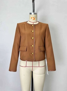 Dettaglio della giacca in tweed marrone con profili in pelle e bottoni dorati