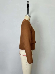 Dettaglio della giacca corta in tweed con bordino in ecopelle marrone e tessuto materico