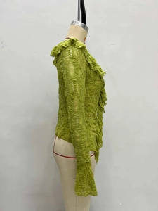 Dettaglio del cardigan verde a maniche lunghe con volant in pizzo e tessuto traforato