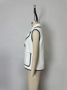 Detail shot of white fleece vest featuring black leather piping and large front pocket