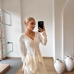 Detail of white lace cardigan with floral hollow patterns and row buttons on V-neck top