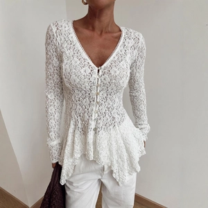 Detailed close-up of white floral lace texture and delicate buttons on a long sleeve top