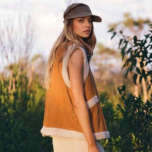 Detail view of brown corduroy vest with white faux fur lining and large side pockets