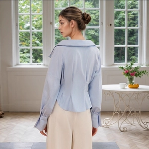 Detail view showing the striped shirt back pleats and tailored waist design with puffy sleeves