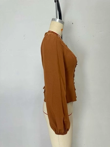 Close-up of rust brown lace puff sleeves and pleated cuffs on a French V-neck blouse