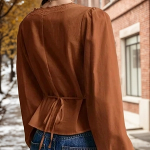 Close-up of caramel lace long-sleeve blouse back with waist tie and delicate V-neck lace trim