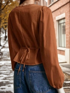 Caramel French lace blouse with V-neck and back tie detail, street lifestyle view