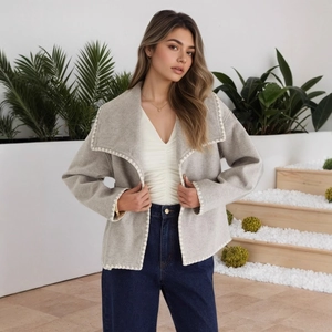 Close-up of light grey wool jacket featuring white contrast embroidery on wide lapels