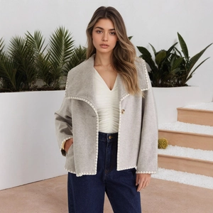 Detailed view of grey wool jacket featuring white triangle embroidery on wide lapels