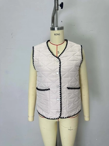 Women's quilted vest in beige with black scalloped trim and diamond pattern on mannequin