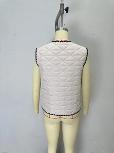 Detail of cream quilted vest with black wavy trim and diamond patterns for autumn layering