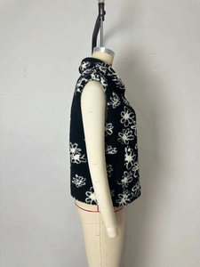 Detail of floral fleece vest showing the high collar, metal zipper, and white flower pattern