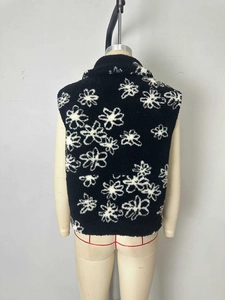 Rear view of a black sleeveless faux shearling vest with white daisy floral print patterns