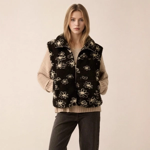 Detail of floral printed fleece vest featuring a stand-up collar and silver metal zipper