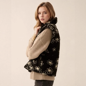 Detail of floral shearling vest layered over a beige knit sweater for winter style