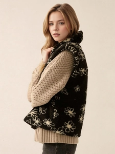 Elegant floral print black fleece vest for women worn over a beige knit sweater