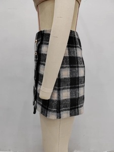 Detail of checkered mini skirt with golden metallic buttons on the side of the fabric