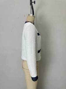 Dettaglio del tessuto in tweed bianco con profili blu navy e bottoni in metallo dorato