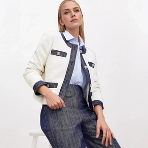 Dettaglio del bordo in denim a contrasto e bottoni dorati goffrati sulla giacca