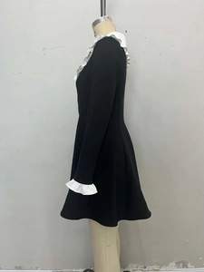 Détail du col volanté blanc et poignets contrastés sur robe trapèze noire élégante