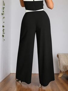 Women's high waist wide leg black trousers shown from back view in a minimalist interior