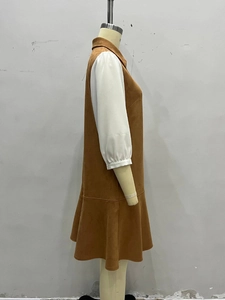 Detail view of brown suede vest dress with white puff sleeves and ruffled hem design