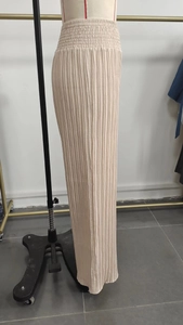 Vue détaillée de la taille haute élastique et du tissu plissé vertical du pantalon beige