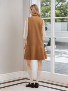 Brown sleeveless suede dress with pleated fisheye hem over white puff sleeve shirt