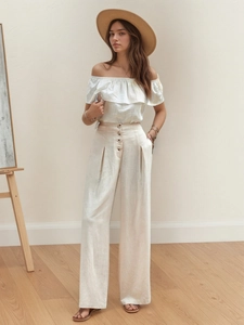 Detailed shot of beige high-waisted wide-leg cotton pants with front button accents
