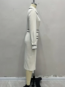 Détail d'une robe blanche à manches longues avec passepoil noir et taille cintrée