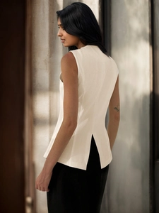 Detail view of the back of a cream sleeveless vest with a stylish vertical slit hem design