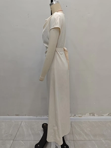 Detail of elegant champagne satin dress featuring pleated neckline and tied waist belt