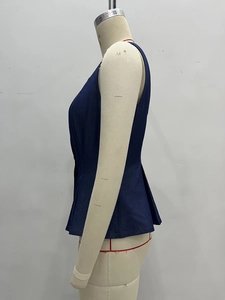 Side view of a dark blue denim vest with a cinched waist and pleated peplum hemline