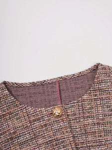 Détail du col rond et du bouton doré sur un gilet en tweed rose texturé