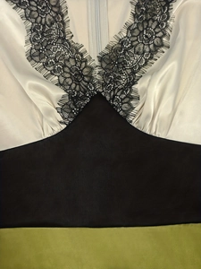 Detail des V-Ausschnitts mit schwarzer Wimpernspitze und dreifarbigen Satin-Einsätzen