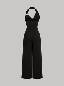 Detail of elegant black halter jumpsuit featuring a gold metal buckle on the shoulder strap