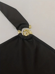 Detailed close-up of golden S-shaped buckle and metal ring on black jumpsuit strap