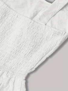 Detailed view of floral jacquard fabric and elastic smocked waist on a white vintage dress