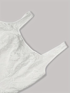 Detailed close-up of white dress fabric with embossed floral jacquard patterns