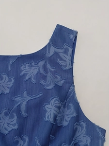 Detail des blauen Jacquard-Kleids mit Blattmuster und Fransen am Ausschnitt