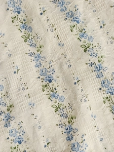 Détail du tissu seersucker blanc avec imprimé floral de roses bleues verticales