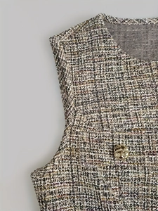 Détail d'un gilet en tweed multicolore avec col rond et bouton doré texturé décoratif