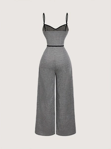 Detail of elegant black and white gingham jumpsuit with spaghetti straps and waist belt