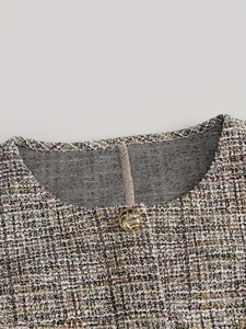 Détail macro du tissu en tweed multicolore et du bouton doré sur l'encolure du gilet