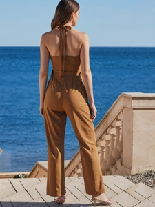 Back view of elegant backless halter jumpsuit in earth tone with wide leg and belt loops
