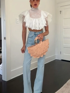 Detail of white lace high neck crop top with layered ruffles and sheer mesh panels
