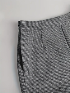 Close-up of grey plaid wool skirt fabric texture with hidden side zipper and waist darts